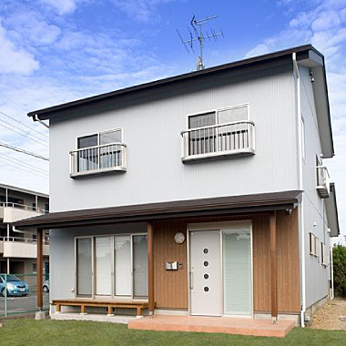 玄関まわりやウッドデッキの木質感と、扉や手すりの素材の質感が調和した外観の写真